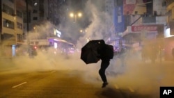 2020年元月1日，香港一名抗議者在警方施放催淚彈時撐著雨傘。