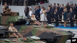 FILE - Tanks parade past President Donald Trump, first lady Melania Trump, French President Emmanuel Macron and his wife, Brigitte Macron, during Bastille Day parade on the Champs Elysees avenue in Paris, July 14, 2017.
