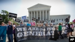 Demonstrators stand on the steps outside the Supreme Court in Washington, June 30, 2014.