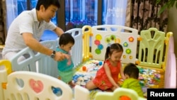 FILE - Tony Jiang poses with his three children at his house in Shanghai September 16, 2013. In December 2010, Jiang, a Shanghai businessman and his wife welcomed a daughter, born in California to an American surrogate he calls "my Amanda".