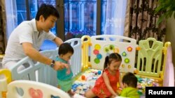 Tony Jiang poses with his three children at his house in Shanghai.