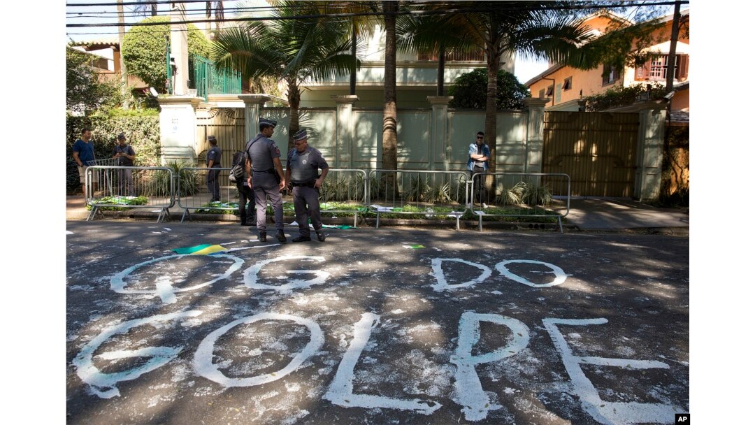 FILE - Police stand guard outside the residence of Brazil's Vice President Michel Temer where demonstrators wrote the words in Portuguese "Coup headquarters" on the street in Sao Paulo, Brazil, April 21, 2016.