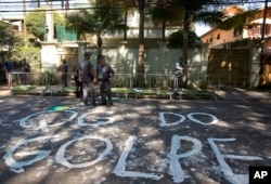 FILE - Police stand guard outside the residence of Brazil's Vice President Michel Temer where demonstrators wrote the words in Portuguese "Coup headquarters" on the street in Sao Paulo, Brazil, April 21, 2016.