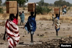 FILE - Women carry boxes of nutritional food delivered by the United Nations World Food Program, in Rubkuai, South Sudan, Feb. 16, 2017.