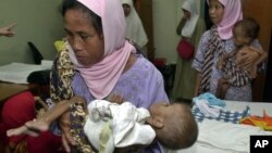 FILE - Indonesian mothers carry their children who suffer from malnutrition at a clinic in Bogor, West Java, Indonesia, June 21, 2005. 