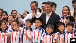 China's President Xi Jinping (center right) and Hong Kong's Chief Executive Leung Chun-ying (center left) give thumbs up as they pose for photographs with members of the Hong Kong Police Force's Junior Police Scheme during a visit to a youth camp in Hong Kong, June 30, 2017. 