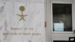 An embassy staffer peers through a glass door at an entrance of the Saudi Arabian embassy in Washington, DC, October 11, 2011.