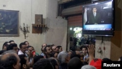 Anti-President Mohamed Morsi protesters watch a speech by him on TV at a cafe in Tahrir Square in Cairo, July 2, 2013.