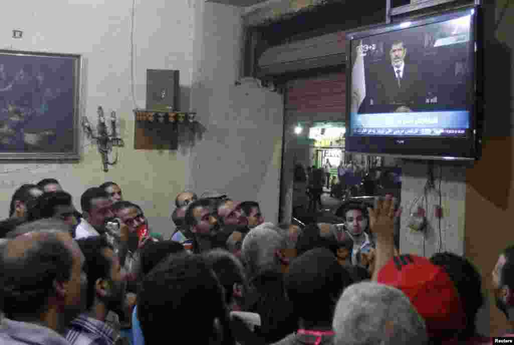 Anti-President Mohamed Morsi protesters watch a speech by him on TV at a cafe in Tahrir Square in Cairo, July 2, 2013.