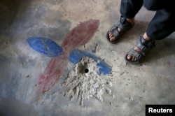 Seorang anak laki-laki menunjukkan lubang di lantai rumahnya yang disebabkan oleh alat yang menurut keluarga seperti mainan dan kemudian meledak di tangan seorang anak, di Desa Jabri, di Lembah Neelum, wilayah Kashmir yang dikuasai Pakistan, 9 Agustus 2019. (Foto: Reuters)
