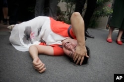 Fan Lili, the wife of imprisoned activist Gou Hongguo, lies on the ground in tears following an interaction with a plainclothed police officer outside the Tianjin No. 2 Intermediate People's Court in Tianjin, China on Aug. 1, 2016.