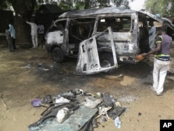 Men inspect a bus following an explosion on the street in Potiskum, Nigeria, Feb. 24, 2015.