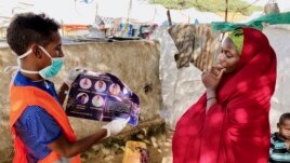 In this photo taken Wednesday, June 10, 2020, an internally-displaced Somali woman, right, is informed how to protect herself from the coronavirus, at the Weydow IDP camp in Mogadishu, Somalia. (Hamza Osman/International Organization for Migration (IOM)