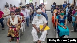 People wait to receive COVID-19 vaccine at a vaccination center in Mumbai, India, Thursday, Sept. 23, 2021.