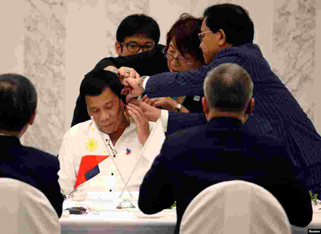 Philippine President Rodrigo Duterte is helped by interpreters to attach an earphone as he attends a luncheon meeting with Japanese business leaders in Tokyo, Japan.