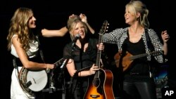 FILE - In this Oct. 18, 2007 file photo, Emily Strayer, left, and Martie Maguire, right, adjust Natalie Maines' hair as the Dixie Chicks perform at the new Nokia Theater in Los Angeles. The group have dropped the word dixie from their name and are now going by The Chicks. (AP)