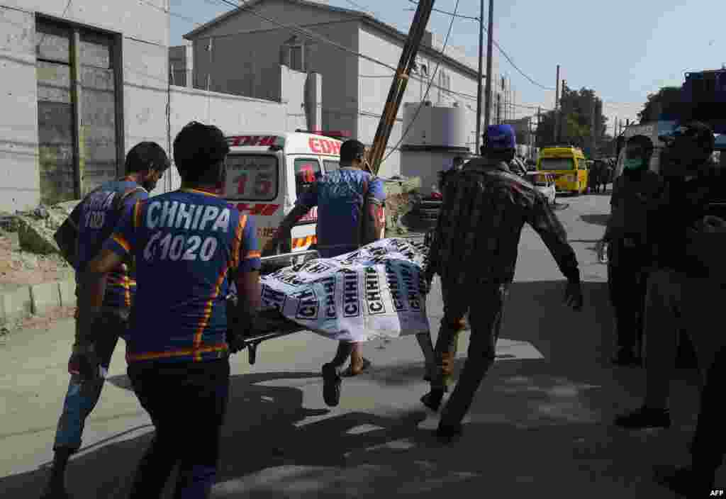 Pakistani ambulance volunteers transport a dead body in front of the Chinese consulate after an attack in Karachi on Friday. At least two policemen were killed when unidentified gunmen stormed the Chinese consulate in the port city of Karachi.