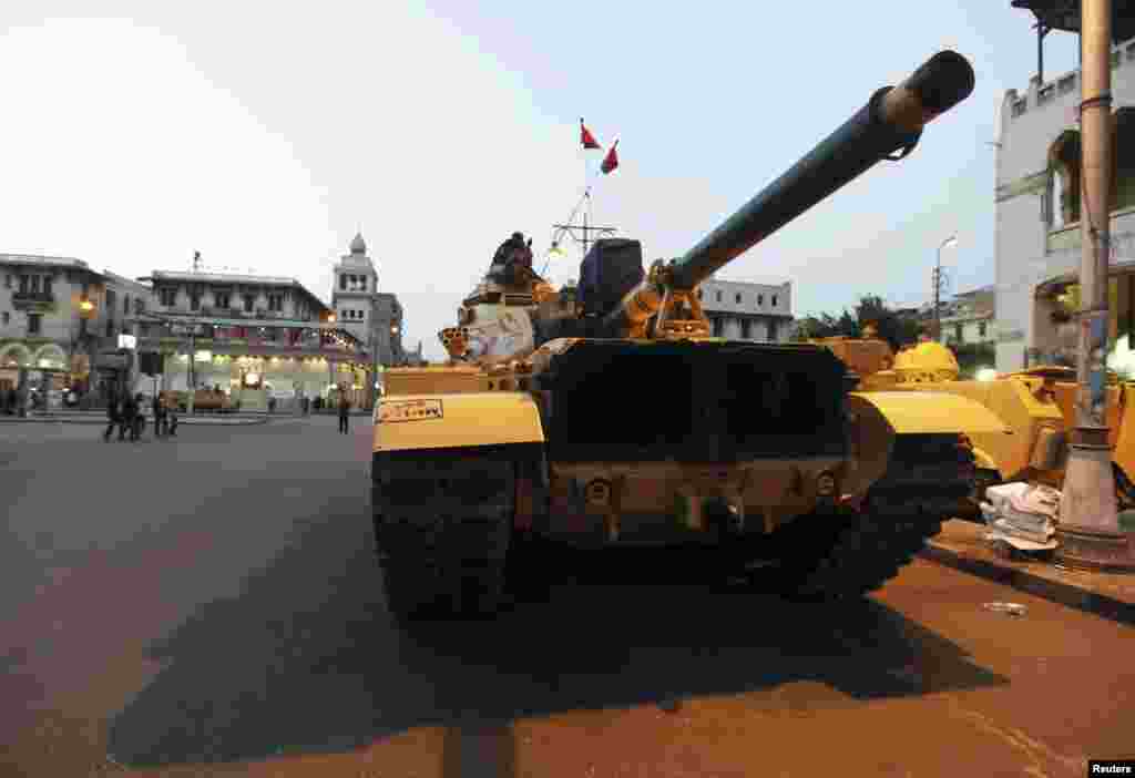 Anti-Mursi protesters walk near a military tank in front of the presidential palace in Cairo, Egypt, December 8, 2012.
