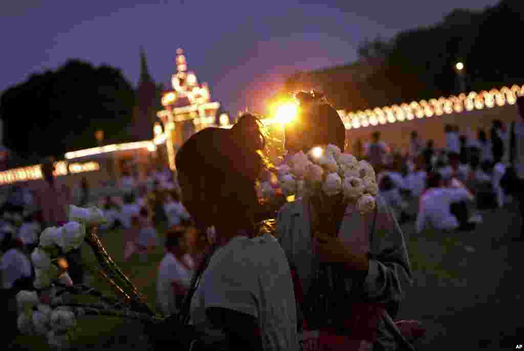 Cambodian girls selling flowers as offerings stand at the entrance of the Royal Palace where the body of the late Cambodian King Norodom Sihanouk body rests, ahead of his funeral, Thursday, Jan. 31, 2013, in Phnom Penh, Cambodia. The body of Sihanouk who died on Oct. 15, 2012 at age 89, is scheduled to be cremated on Feb. 4, 2013. (AP Photo/Wong Maye-E)