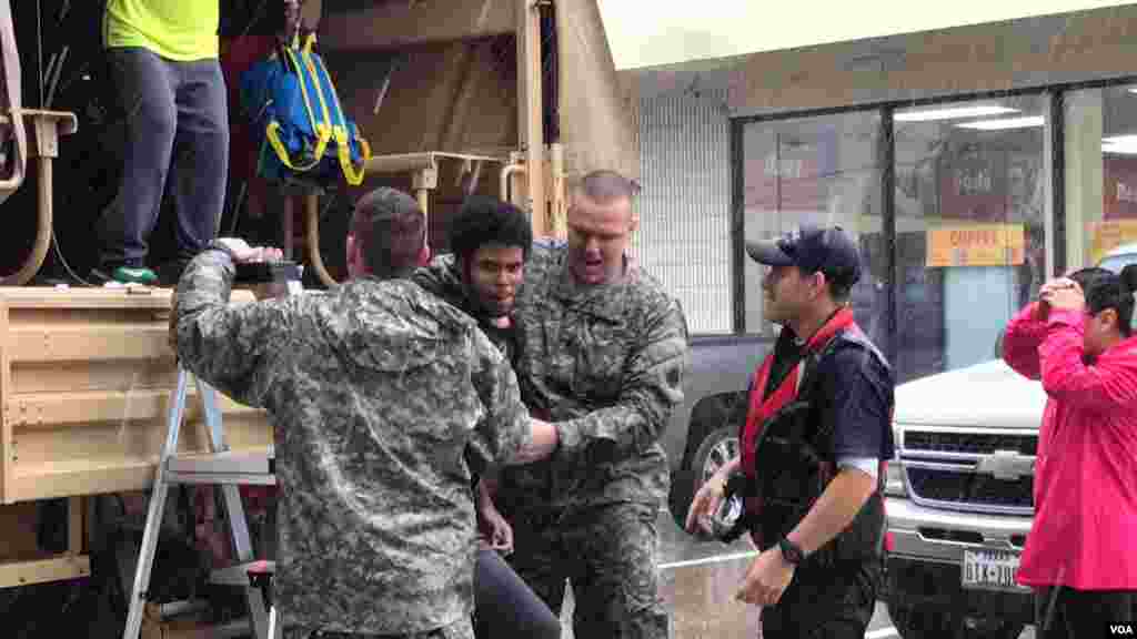 Rescuers assist flood victims out of a military transport vehicle at a gas station doubling as a transfer point in north Houston, Texas, Aug. 27, 2017. Retrieved from the Greenbriar Colony neighborhood, they’ll go on to a Red Cross shelter. (C. Mendoza/VO