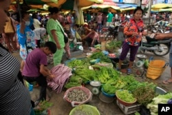 Local residents buy fresh vegetables at a morning market in Phnom Penh, Cambodia, Nov. 8, 2015. With interest accumulated over the years, Cambodia today owes the U.S. about half a billion dollars.