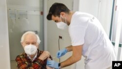 FILE - The patient Kurt Switil, left, receives a Pfizer vaccination against the COVID-19 disease by a doctor in the vaccination center ‚Am Schoepfwerk' in Vienna, Austria, April 10, 2021. The Austrian government ordered a nationwide lockdown for unvaccina