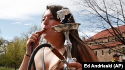 FILE - A student uses a water pipe to smoke marijuana outside the police barrier on the Norlin Quad at the University of Colorado in Boulder, Colorado, on Friday, April 20, 2012. (AP Photo/Ed Andrieski)