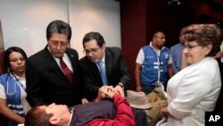 El ministro de relaciones exteriores de El Salvador, Jaime Miranda y otros funcionarios saludan a Alvarenga mientras descansa en una camilla donde revisan sus signos vitales.