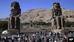 Tourists look at the Colossi of Memnon, two massive stone statues of Pharaoh Amenhotep III, on the west bank of the Nile River at Luxor, 510 kilometers (320 miles) south of Cairo, Egypt, Monday, Dec. 1, 2014. (AP Photo/Hassan Ammar)