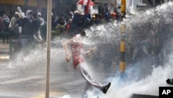 Un manifestante patea una contenedor de gas lacrimógeno en Bogotá.