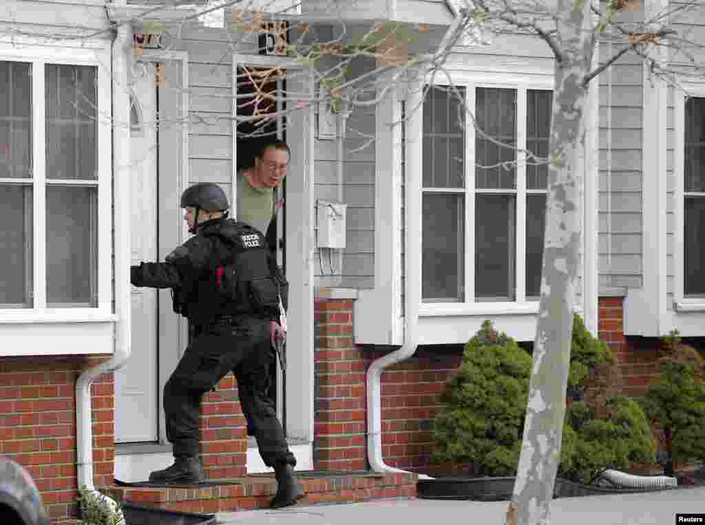 A man looks out of his door as a SWAT team member knocks on his neighbors door as they search for the remaining suspect in the Boston Marathon bombings in Watertown, Massachusetts April 19, 2013. 
