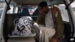 A relative mourns next to the body of a female polio vaccination worker killed by gunmen in Quetta, Pakistan, Jan. 18, 2018.