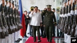 Philippine President Rodrigo Duterte, center left, salutes the troops with Armed Forces Chief Gen. Ricardo Visaya before boarding his flight for a three-day official visit to Japan at the Ninoy Aquino International Airport in suburban Pasay city, south of