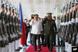 FILE - Philippine President Rodrigo Duterte, center left, salutes the troops with Armed Forces Chief Gen. Ricardo Visaya before boarding his flight for a three-day official visit to Japan.