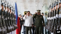 Philippine President Rodrigo Duterte, center left, salutes the troops with Armed Forces Chief Gen. Ricardo Visaya before boarding his flight for a three-day official visit to Japan at the Ninoy Aquino International Airport in suburban Pasay city, south of