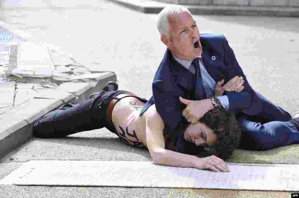 Zaštitar pred zdanjem Evropske komisije u Briselu, drži oborenu aktivistkinju grupe Femen, koja je zajednos sa drugim prosvjednicama izražavala nezadovoljstvo posjetom premijera Tunisa sjedištu EU.