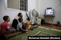 FILE - A Free Syrian Army fighter watches U.S. President Barack Obama's speech with his family in Ghouta, Damascus August 31, 2013.