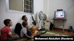 A Free Syrian Army fighter watches U.S. President Barack Obama's speech with his family in Ghouta, Damascus August 31, 2013. Obama on Saturday backed away from an imminent military strike against Syria to seek the approval of the U.S. Congress, in a decis