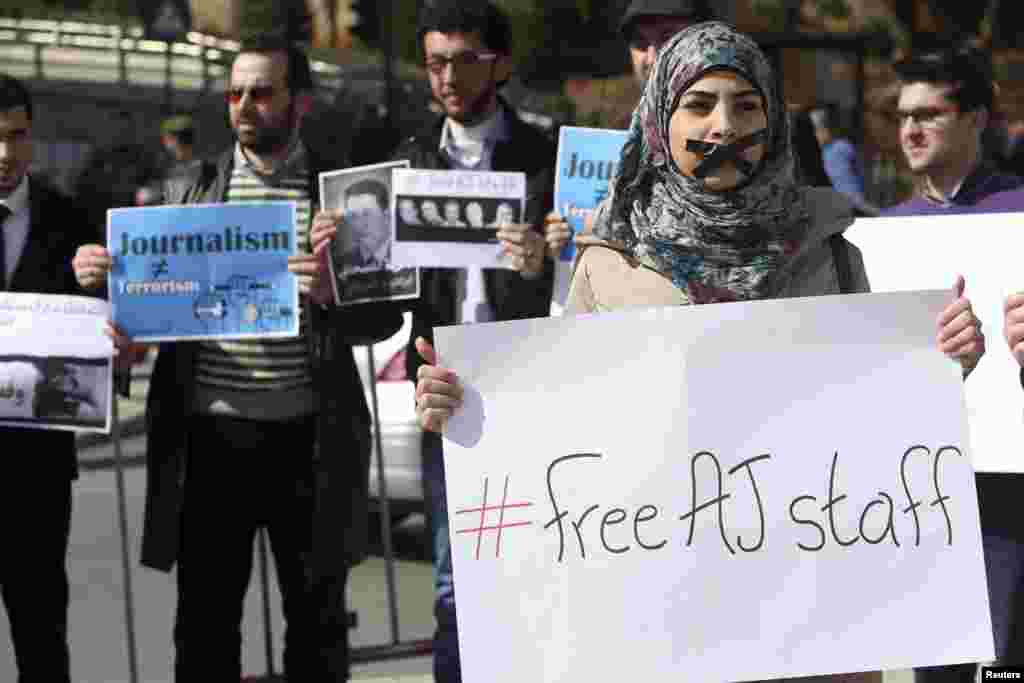 A protester, with a taped mouth, stands with a sign during a protest in Beirut, Lebanon, against the detainment of Al Jazeera journalists in Egypt.