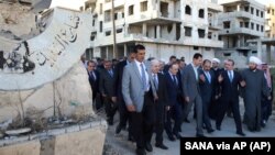 Foto divulgada por la agencia estatal de noticias siria, SANA, del presidente Bashar al Assad, centro, en los suburbios de Daraya, Damasco.