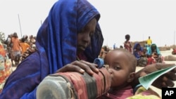 FILE - A mother quenches her malnourished child's thirst while waiting for food handouts at a health center in drought-stricken remote Somali region of Eastern Ethiopia, also known as the Ogaden.