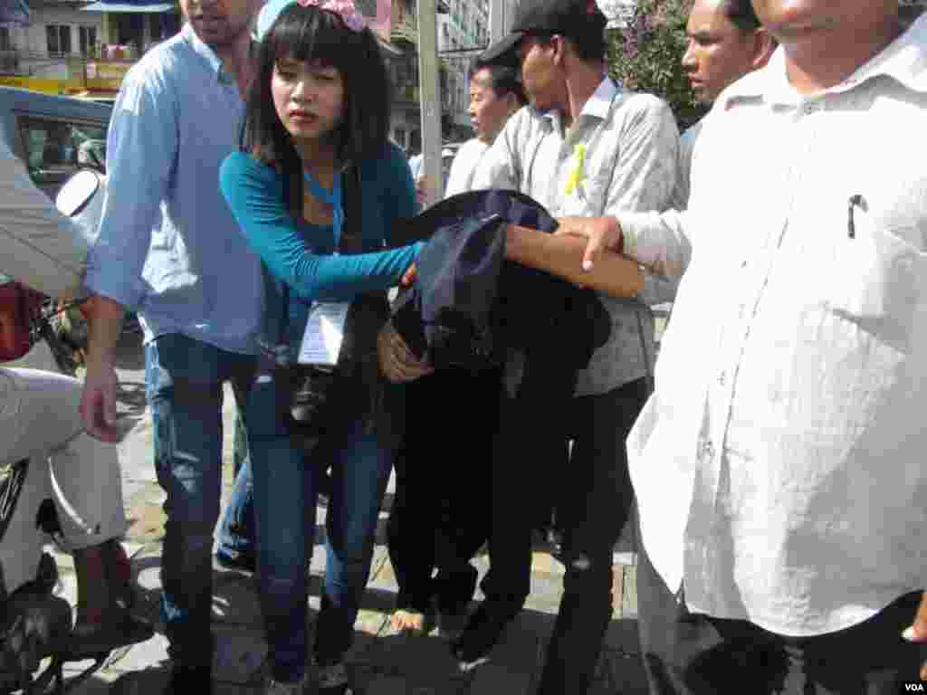 Opposition activists and human rights officials protect a security guard from being attacked by angry protesters,&nbsp;Phnom Penh, Cambodia, July 15, 2014. (Khoun Theara/VOA)