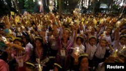 Warga Thailand memegang lilin dan foto Raja Thailand Bhumibol Adulyadej di rumah sakit Siriraj, di mana sekelompok orang berkumpul untuk merayakan ulang tahunnya yang ke-88, di Bangkok, Thailand, 5 Desember 2015. 