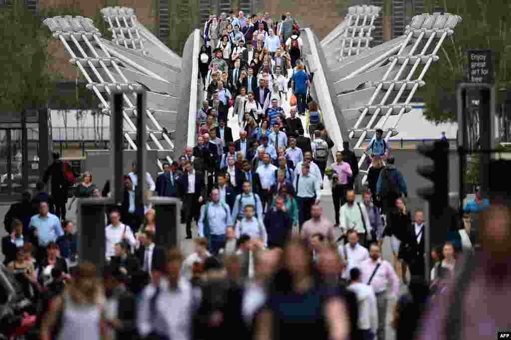 Commuters cross the River Thames on the Millennium footbridge as a tube strike hits the morning rush hour in the city of London. Millions of Londoners were forced to walk, cycle or take packed buses to work as Underground staff staged a second strike in a month over plans to run trains all night at weekends. London Underground staff walked out yesterday evening and will not return until the morning of August 7, causing a shutdown of all 11 lines on the subway network and severely disrupting the capital.