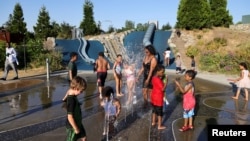 Adults and kids play in a spray park at Jefferson Park during a heat wave in Seattle, Washington, U.S., June 27, 2021. REUTERS/Karen Ducey