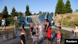 Orang dewasa dan anak-anak bermain air di Jefferson Park saat gelombang panas melanda Seattle, Washington, AS, 27 Juni 2021. (REUTERS/Karen Ducey)