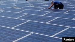 一名工人在日内瓦展览中心的屋顶上安装太阳能电池板