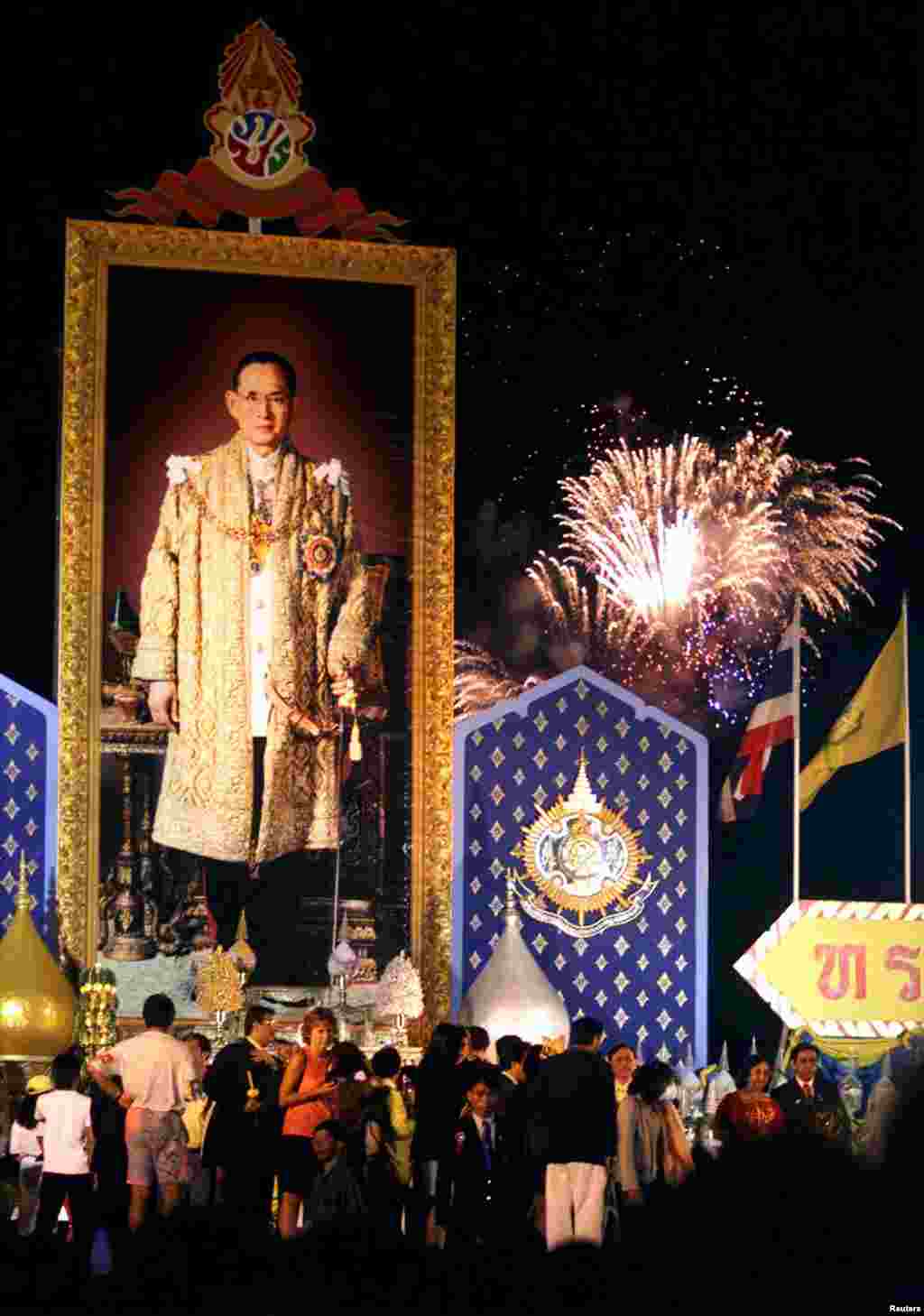 A portrait of Thailand&#39;s King Bhumibol Adulyadej (L) adorns a stage as fireworks explode over Bangkok, Dec. 5, 1999, in celebration of the king&#39;s 72nd birthday.