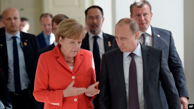 Russian President Vladimir Putin and German Chancellor Angela Merkel speak to each other before the World Cup final between Germany and Argentina in Rio de Janeiro, Brazil.