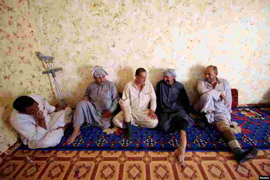 Rafed, a man disabled by a landmine explosion, chats with friends in the village of Bitr, which in Arabic means &quot;amputation&quot;, in Al-Tanouma district, east of Basra, Iraq.